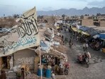 People walk through a market with old Taliban flags flown above in a town in a remote region of Afghanistan.