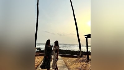 This photo shows Suhana enjoying the sunset with her friend. She wore a white floral printed midi dress for the outing. It features puffed half-length sleeves, a wide neckline, a smocked bodice, a figure-hugging silhouette, and a slit on the back. She wore it with a shoulder bag and open locks. (Instagram) This photo shows Suhana enjoying the sunset with her friend. She wore a white floral printed midi dress for the outing. It features puffed half-length sleeves, a wide neckline, a smocked bodice, a figure-hugging silhouette, and a slit on the back. She wore it with a shoulder bag and open locks. (Instagram)