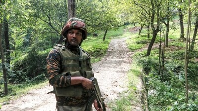 A security personnel stands guard during a cordon and search operation in the higher reaches of the Halan forest area of Kulgam district in south Kashmir on Saturday, following inputs about the presence of terrorists. (ANI Photo)