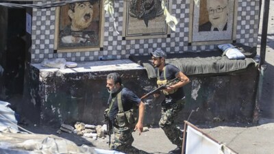 Members of the Palestinian Fatah group run to take position during a third day of clashes that erupted with Islamist factions in the Palestinian refugee camp of Ein el-Hilweh near the southern port city of Sidon, Lebanon, on July 31, 2023. (AP)