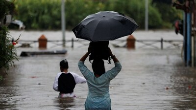 Nepal Floods: People walk along a flooded road near the bank of overflowing Bagmati river following heavy rains, in Kathmandu. (Reuters)
