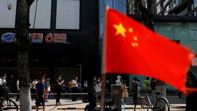 A China's flag flutters near people lining up to get tested at a makeshift nucleic acid testing site. (File image) (REUTERS)
