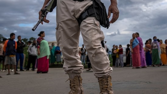 A Manipur policeman stands guard as members of Meira Paibis, powerful vigilante group of Meitei women, block traffic to check vehicles for members from rival tribal Kuki community, in Imphal, on June 19. (AP)