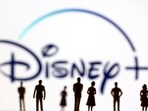 FILE PHOTO: Toy figures of people are seen in front of the displayed Disney + logo, 