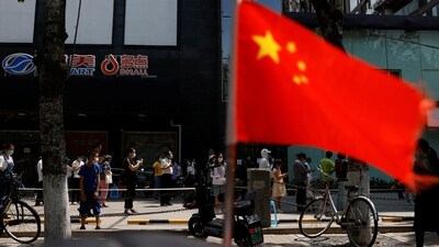 A China's flag flutters near people lining up to get tested at a makeshift nucleic acid testing site. (File image) (REUTERS)