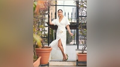 Kareena's white dress features wide notch-lapel collars, a plunging V neckline highlighting her decolletage, quarter-length sleeves, a gold buckle embellishment on the front, cinched waistline, gathered design, a figure-hugging silhouette, a thigh-high slit, and a midi hem length. (Instagram) Kareena's white dress features wide notch-lapel collars, a plunging V neckline highlighting her decolletage, quarter-length sleeves, a gold buckle embellishment on the front, cinched waistline, gathered design, a figure-hugging silhouette, a thigh-high slit, and a midi hem length. (Instagram)