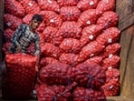 A worker unloads sacks of onions from a truck, at a wholesale vegetable market in Jalandhar