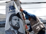 An electrician works next to a political advertisement of Ecuador's presidential candidate Jan Topic in Quito on August 12, 2023. 