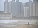 A man walks along a beach during winds brought on by Typhoon Khanun at the southeastern port city of Busan.