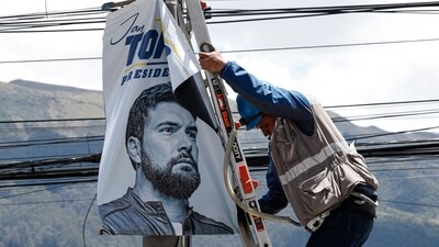 An electrician works next to a political advertisement of Ecuador's presidential candidate Jan Topic in Quito on August 12, 2023. (AFP) An electrician works next to a political advertisement of Ecuador's presidential candidate Jan Topic in Quito on August 12, 2023. (AFP)