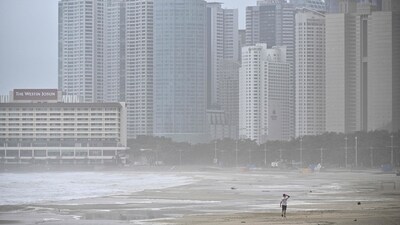 A man walks along a beach during winds brought on by Typhoon Khanun at the southeastern port city of Busan. (AFP)