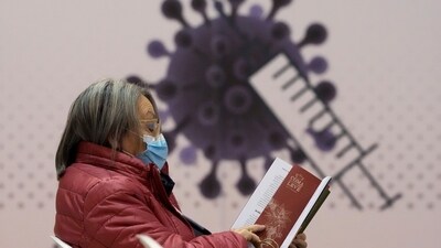 A woman reads a book in the recovery area of a new vaccination center. (AP File) A woman reads a book in the recovery area of a new vaccination center. (AP File)
