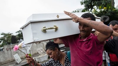 Gilgres Santos, the father of five-year-old Eloah Passos, carries his daughter's remains for a burial at Cacuia Cemetery two days after she was killed by a stray bullet in Rio de Janeiro, Brazil, Monday. (AP)
