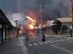 People watch as smoke and flames fill the air from raging wildfires on Front Street in downtown Lahaina, Maui on Tuesday, Aug. 8, 2023. (Alan Dickar via AP)
