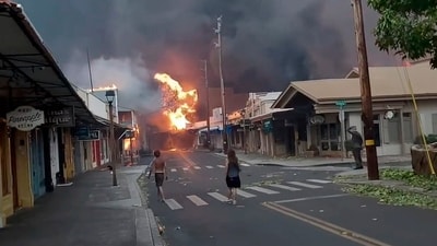 People watch as smoke and flames fill the air from raging wildfires on Front Street in downtown Lahaina, Maui on Tuesday, Aug. 8, 2023. (Alan Dickar via AP) (AP) People watch as smoke and flames fill the air from raging wildfires on Front Street in downtown Lahaina, Maui on Tuesday, Aug. 8, 2023. (Alan Dickar via AP) (AP)