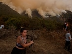 Residents of the town of Aguamansa clean the surroundings of their houses due to the proximity of the fire, as wildfires rage out of control on the island of Tenerife, Canary Islands, Spain. 