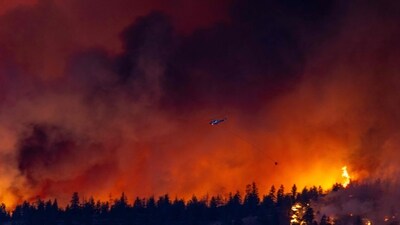 A helicopter battles the McDougall Creek wildfire as it burns in the hills West Kelowna, British Columbia, Canada, (AFP)