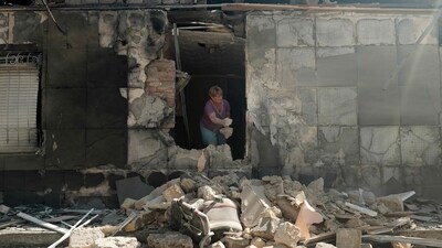 A local resident clear debris in her house destroyed as a result of missiles strike to Kherson (AFP)