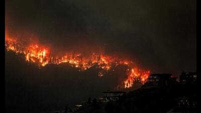Smoke and flames from wildfires serve as a backdrop for homes across Okanagan Lake in West Kelowna, British Columbia, Canada, August 17, 2023. (REUTERS) Smoke and flames from wildfires serve as a backdrop for homes across Okanagan Lake in West Kelowna, British Columbia, Canada, August 17, 2023. (REUTERS)