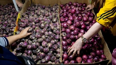 People buy onions displayed at a stall in a public market. (REUTERS)
