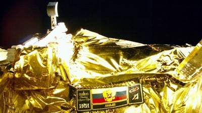 A picture taken from the camera of the lunar landing spacecraft Luna-25 during its flight to the moon shows the mission emblem and the bucket of the lunar manipulator complex, August 15 (Roscosmos)