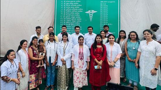 The doctors of Gharivali pose before a hoarding with all their names, which is prominently displayed in the village. (HT Photo)