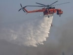 A firefighting helicopter makes a water drop, as a wildfire burns near the village of Asklipieio, on the island of Rhodes, Greece. (Reuters)