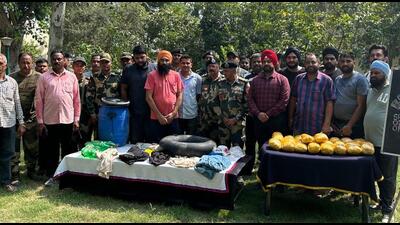 Border Security Force and Punjab Police personnel with the 26 packets of heroin recovered from two Pakistani smugglers in Ferozepur district on Monday. (HT Photo) Border Security Force and Punjab Police personnel with the 26 packets of heroin recovered from two Pakistani smugglers in Ferozepur district on Monday. (HT Photo)