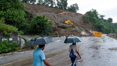 People walk in the rain next to a highway expansion site where heavy rains have disrupted operations and blocked part of the existing road in Dharamshala. (AP) People walk in the rain next to a highway expansion site where heavy rains have disrupted operations and blocked part of the existing road in Dharamshala. (AP)