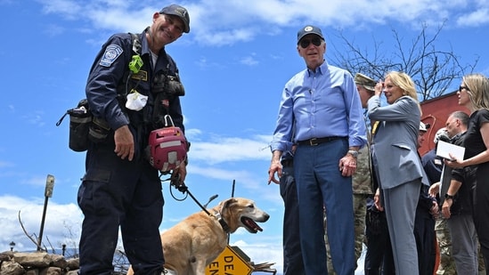 US President Joe Biden (C) greets a dog wearing protective boots as he meets with first responders during an operational briefing on response and recovery efforts following wildfires in Lahaina, Hawaii on August 21, 2023. The Bidens are expected to meet with first responders, survivors, and local officials following deadly wildfires in Maui. (AFP)