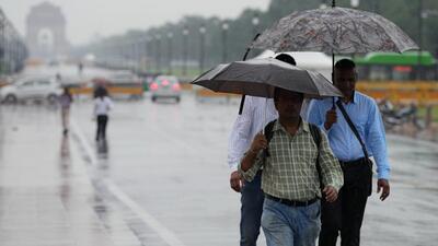People commute to work on foot amid heavy rainfall in New Delhi on Wednesday. (PTI Photo)