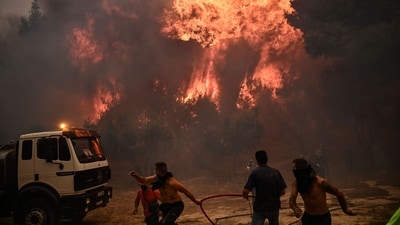 Firefighters and volunteers flee during a wildfire in Chasia in the outskirts of Athens (AFP) Firefighters and volunteers flee during a wildfire in Chasia in the outskirts of Athens (AFP)