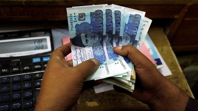A trader counts Pakistani rupee notes at a currency exchange booth in Peshawar, Pakistan December 3, 2018. (REUTERS)