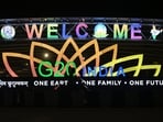 A man rides past an illuminated hoarding with the G20 logo displayed along a street in New Delhi.