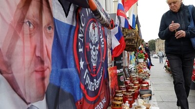 A woman lights a candle at a makeshift memorial for Yevgeny Prigozhin, head of the Wagner mercenary group. (Reuters)