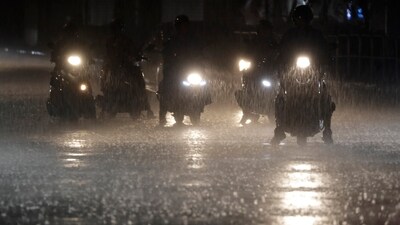 Riders wait at the intersection under heavy rain as the Typhoon Haikui approaches the country. (AP)
