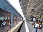 A train is  seen stopped at a railway station. Passengers seen walking by.