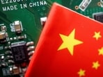 A Chinese flag is displayed next to a "Made in China" sign seen on a printed circuit board with semiconductor chips, in this illustration.