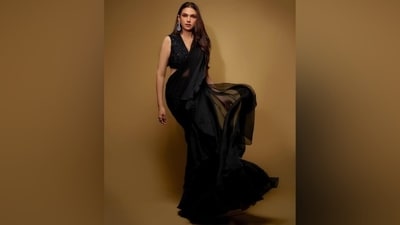 Aditi draped herself in a black chiffon saree adorned in silk ruffle adornments on the border. She wore the six yards in traditional style, letting the pallu fall from the shoulder in floor-grazing length. Aditi matched the saree with a sleeveless black blouse featuring sequin embellishments, a plunging V neckline, a cropped hem, and a fitted silhouette. (Instagram) Aditi draped herself in a black chiffon saree adorned in silk ruffle adornments on the border. She wore the six yards in traditional style, letting the pallu fall from the shoulder in floor-grazing length. Aditi matched the saree with a sleeveless black blouse featuring sequin embellishments, a plunging V neckline, a cropped hem, and a fitted silhouette. (Instagram)