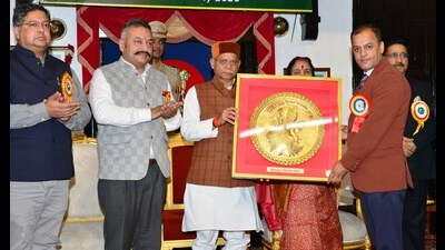 Himachal Pradesh governor Shiv Pratap Shukla presenting an award to a teacher on Tuesday. (HT Photo)