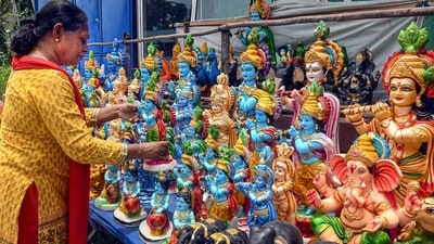 A devotee selects an idol of Lord Krishna to purchase ahead of the Krishna Janmashtami in Thiruvananthapuram, Kerala. (PTI)