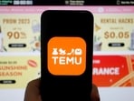 The logo of Temu, an e-commerce platform owned by PDD Holdings, is seen on a mobile phone displayed in front of its website.