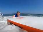 The image shows the swimmer saved by a surfer. The image shows the swimmer saved by a surfer.