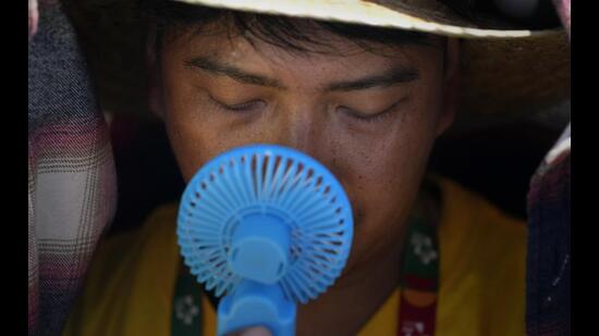 A World Youth Day volunteer uses a small fan to cool off from the intense heat, as he waits ahead of the Pope Francis arrival at Passeio Marítimo in Algés, just outside Lisbon, Aug. 6, 2023. (AP)