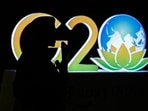 An armed security personnel stands guard near a G20 India summit logo installed along a street in New Delhi on September 6, 2023, ahead of its commencement.