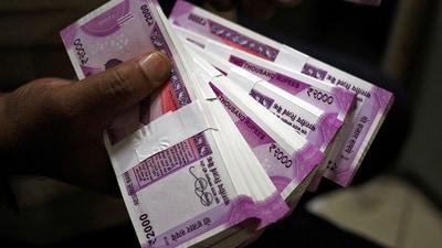 A cashier displays the new 2000 Indian rupee banknotes inside a bank. (REUTERS)