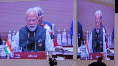 A screen displays Prime Minister Narendra Modi as he sits behind the country tag reading Bharat. (REUTERS) A screen displays Prime Minister Narendra Modi as he sits behind the country tag reading Bharat. (REUTERS)