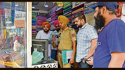 Police at the victim’s shop in GTB Market in Ludhiana on Saturday. (HT)