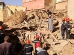 A man gestures next to emergency workers on the rubble, in the aftermath of a deadly earthquake, in Amizmiz, Morocco.