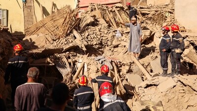 A man gestures next to emergency workers on the rubble, in the aftermath of a deadly earthquake, in Amizmiz, Morocco. (REUTERS)